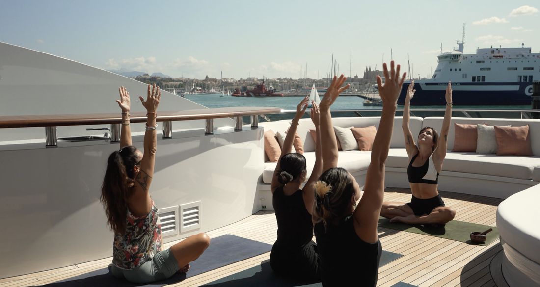 Crew members during a wellbeing session on the deck of a yacht in Palma